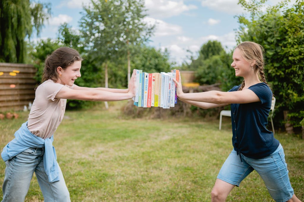 2 tieners duwen tegen een boekenstapel die zweeft in de lucht