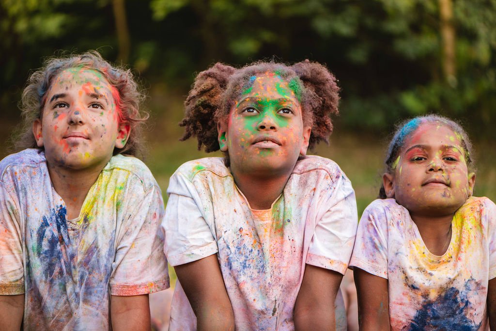3 kinderen in de  yogahoudig van de slang, met kleurpoeder over zich heen